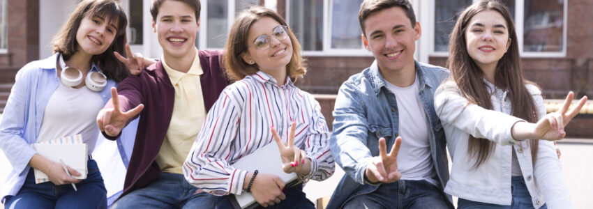 young-people-sitting-with-books-gesturing-two-fingers